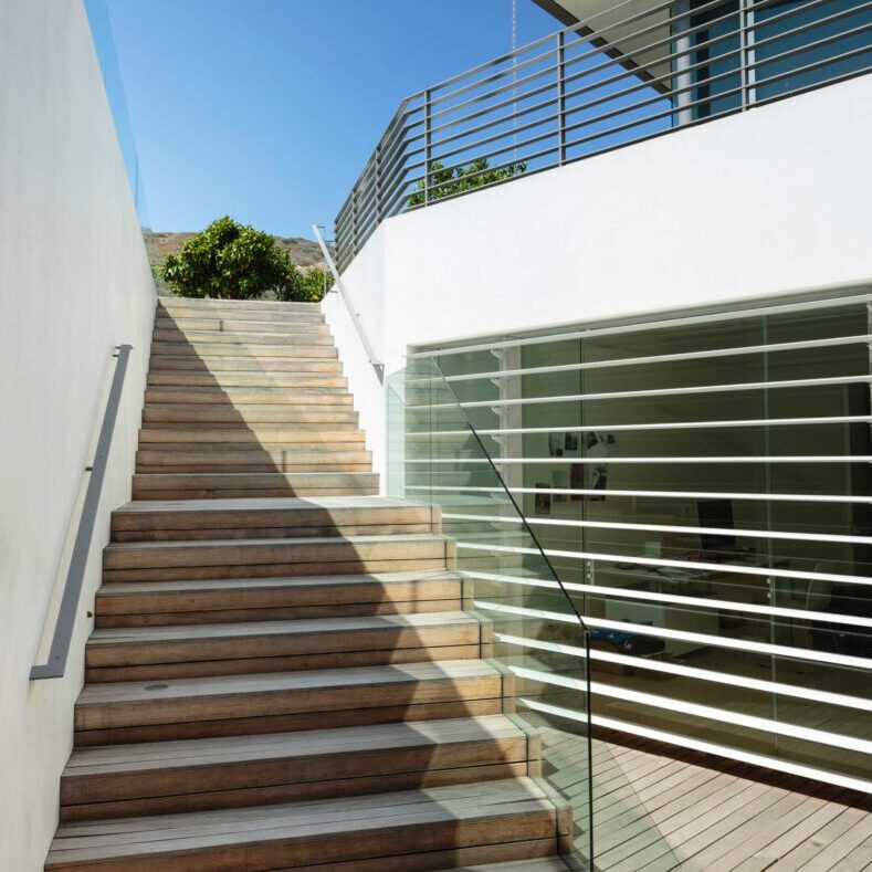 A staircase leading up to a house with glass railings.