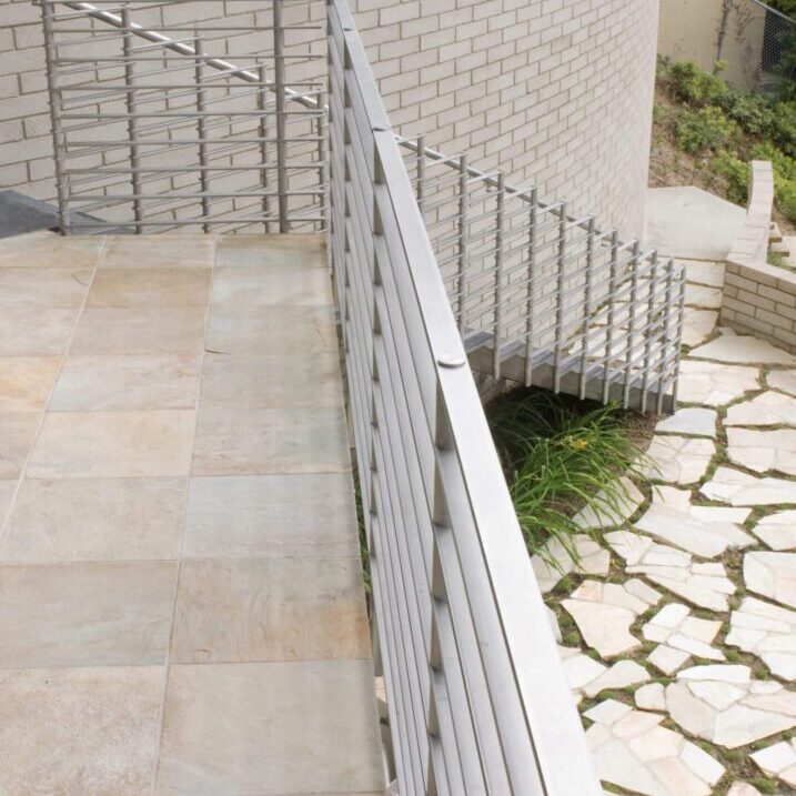 A metal railing with a stone path in front of a house.